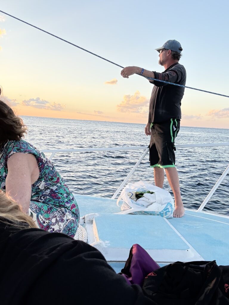Man standing on a double-decker dive boat viewing the sunset in Cozumel, Mexico