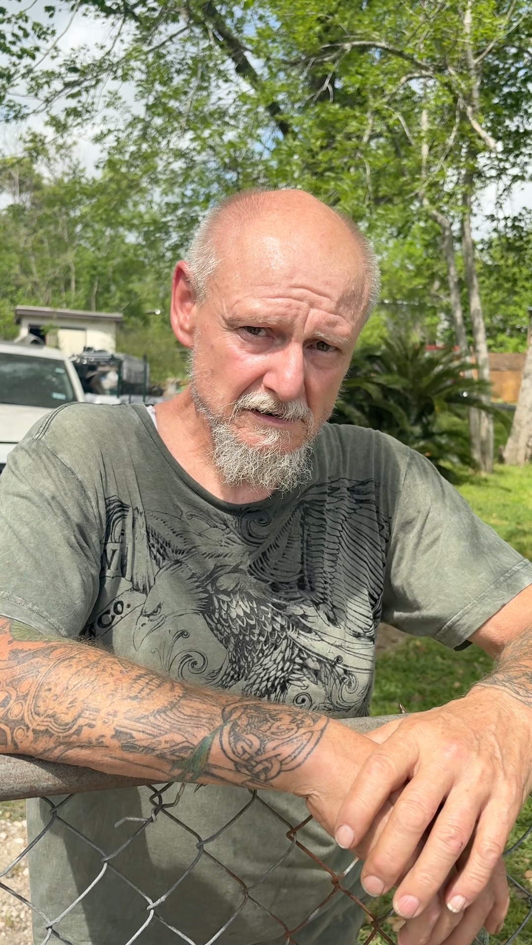 Raymond Elmore standing behind a chain link fence on his property in Texas, which was searched by investigators as part of the Texas Killing Fields case.