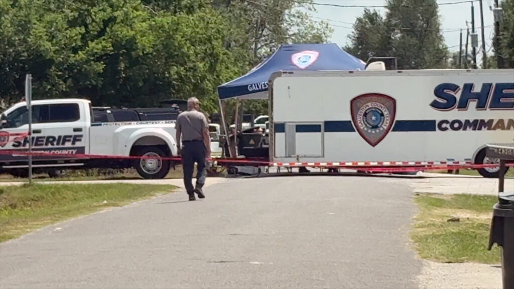 Sheriff's command vehicle with law enforcement officers walking toward it during an active investigation scene.