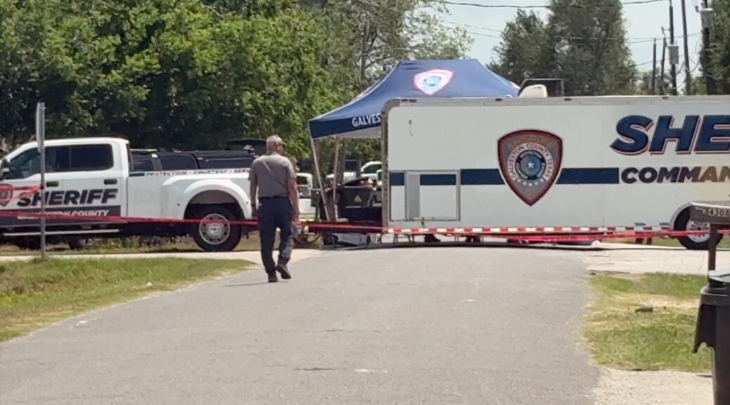 Sheriff's command vehicle with law enforcement officers walking toward it during an active investigation scene.