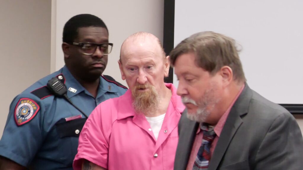 James Elmore Jr. stands beside his attorney and a courtroom deputy during a Galveston County pretrial hearing.

