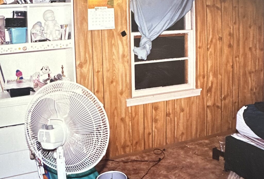 Interior of a bedroom in the home linked to the Becky Beard murder investigation, showing a window, wooden walls and a fan.