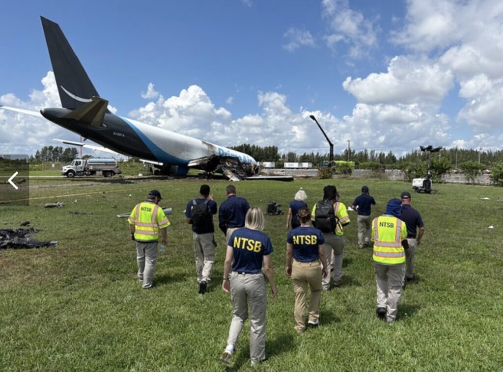 NTSB investigators walk toward the wreckage of a Boeing 767 cargo jet at Miami International Airport.