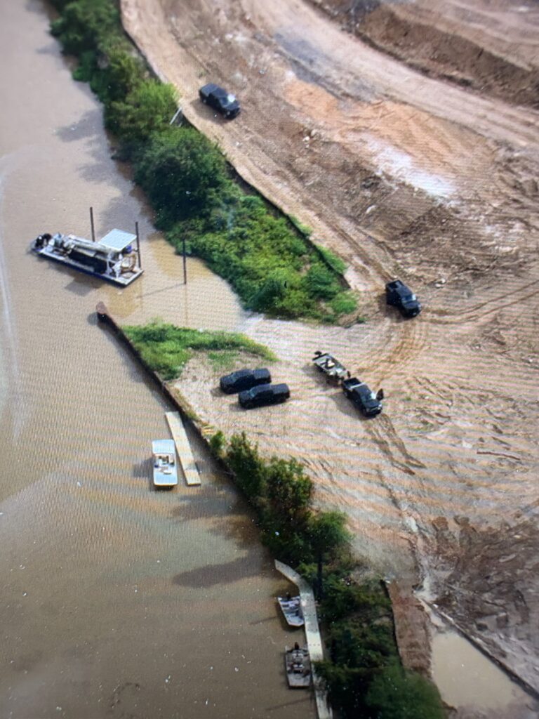 Aerial view of Buffalo Bayou with rescue boats and emergency vehicles along the shoreline